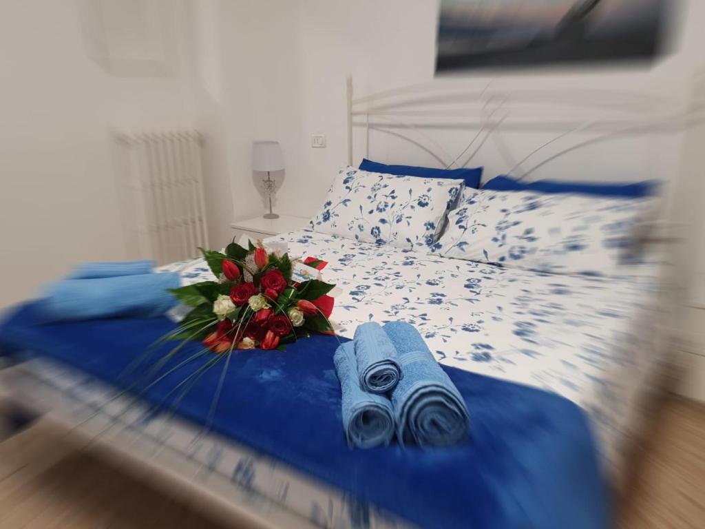 een bed met blauwe lakens en een boeket bloemen erop bij Mare D’amare in San Benedetto del Tronto