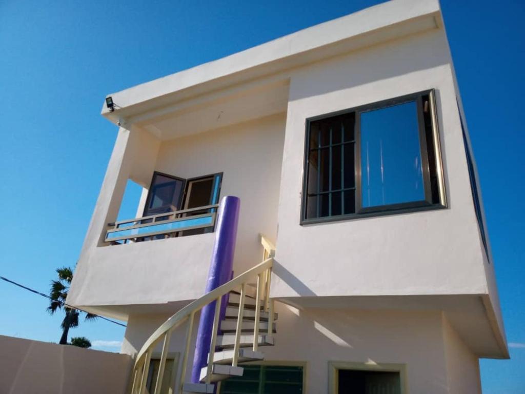 una casa blanca con una barandilla de escalera púrpura en Vue sur l'Atlantique, en Cotonou