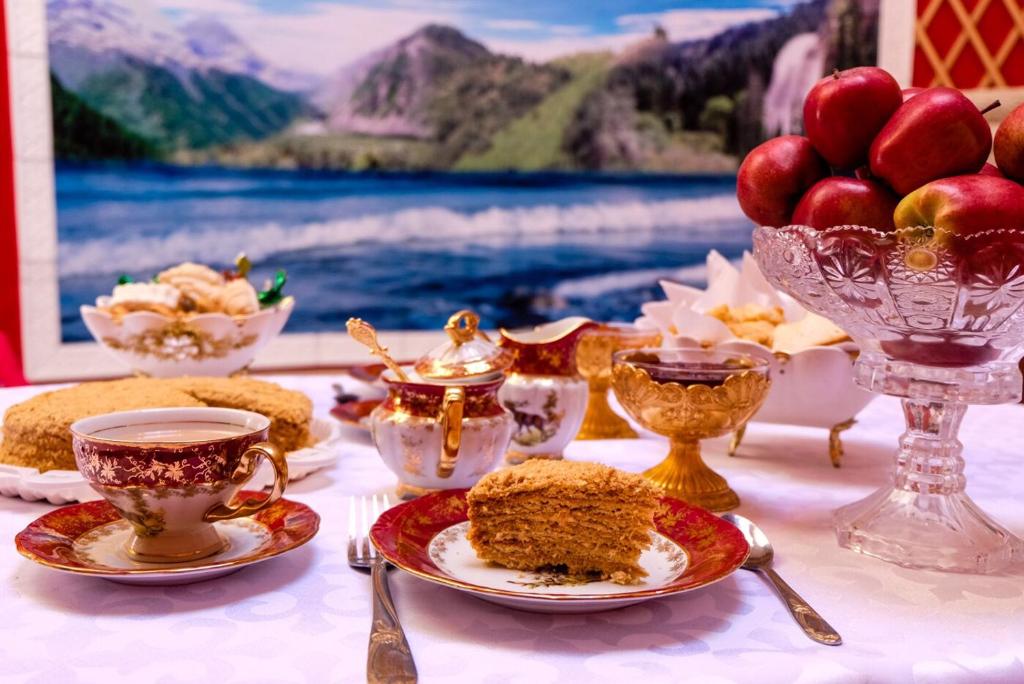 un tavolo con tazze e piatti di cibo e frutta di Barskoon Guest House a Barskoon