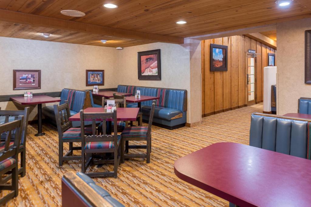 ein Esszimmer mit Tischen, blauen Stühlen und einem Tisch in der Unterkunft Thunderbird Lodge in Chinle