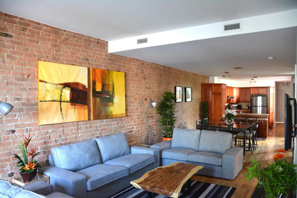 a living room with blue couches and a brick wall at Le Metro Mont-Royal by HomeInMontreal in Montréal