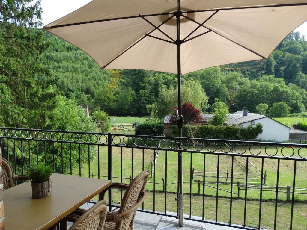 a table and chairs with an umbrella on a balcony at Studio Eveux in La-Roche-en-Ardenne