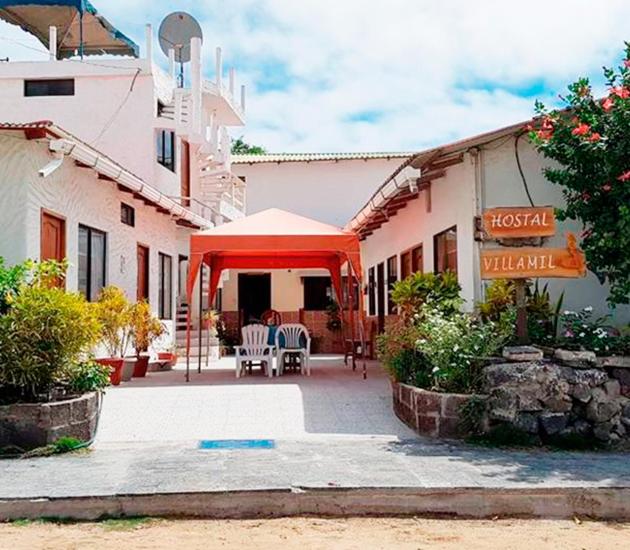 a patio with a red tent and chairs in front of a building at Hostal Villamil in Puerto Villamil