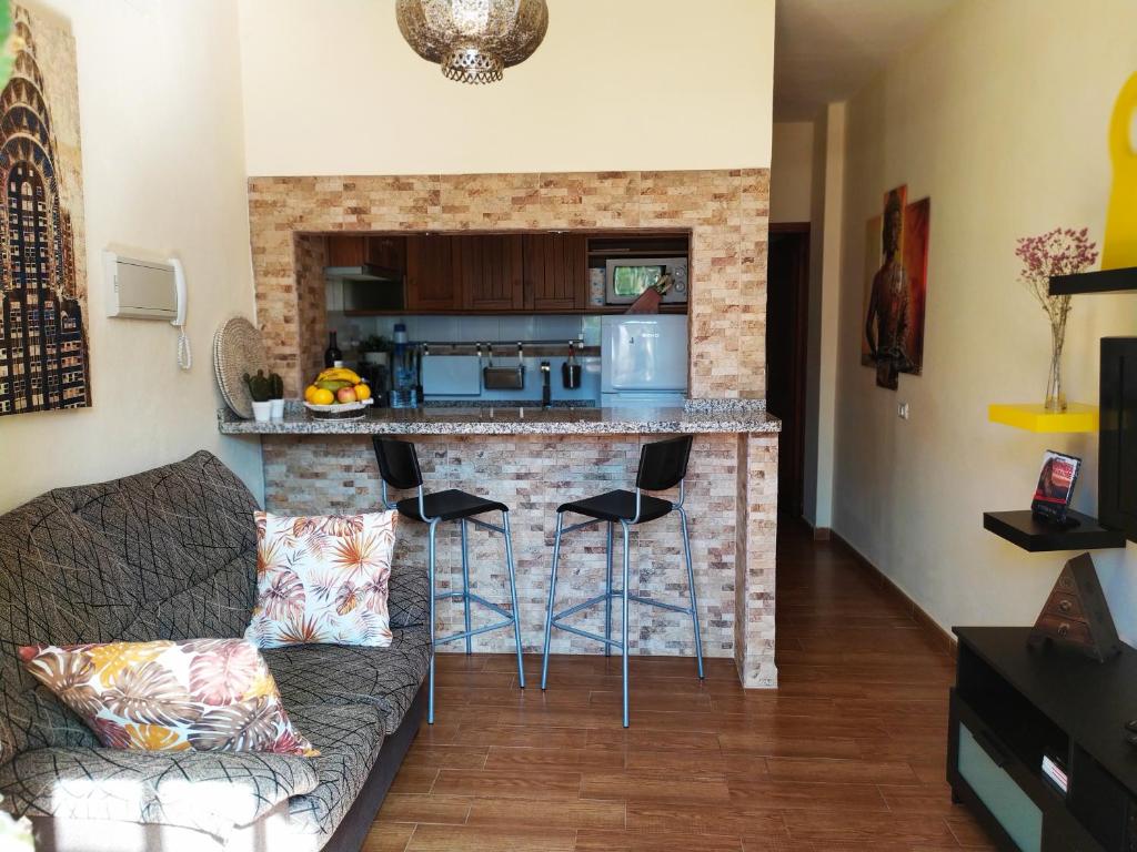 ein Wohnzimmer mit einer Küche und einer Bar mit Hockern in der Unterkunft Apartamento La Peatonal in San Sebastián de la Gomera