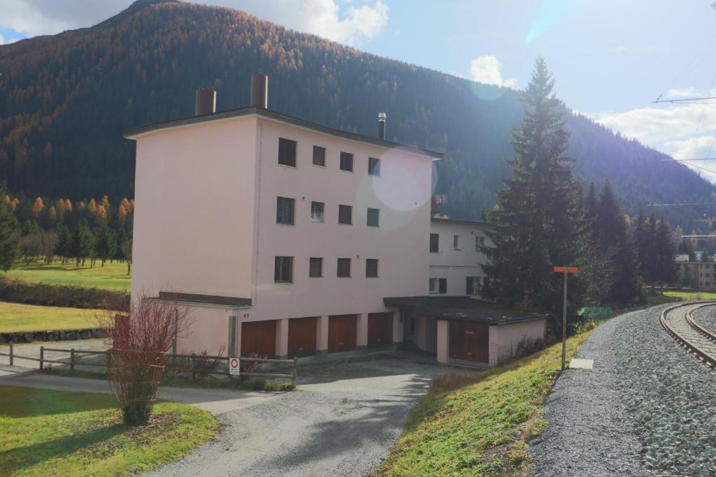 a large white building with a mountain in the background at Golf Apartments - Schmid in Davos