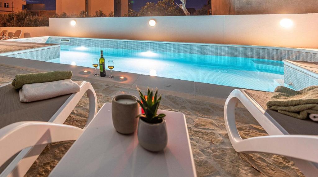 a table and chairs next to a swimming pool at Apartman Tea in Novalja