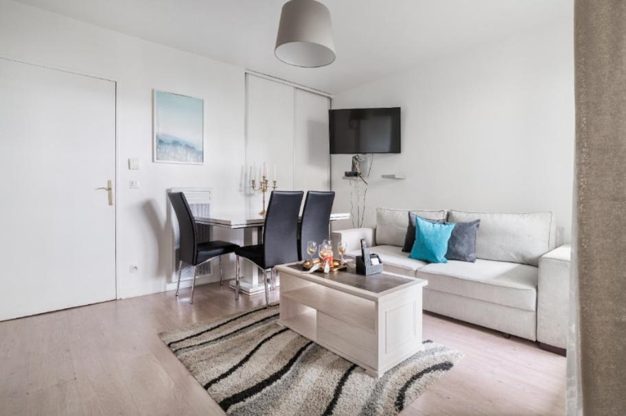 - un salon avec un canapé, une table et une salle à manger dans l'établissement Appartement spacieux avec terrasse près de Paris et du Stade de France, à Saint-Denis