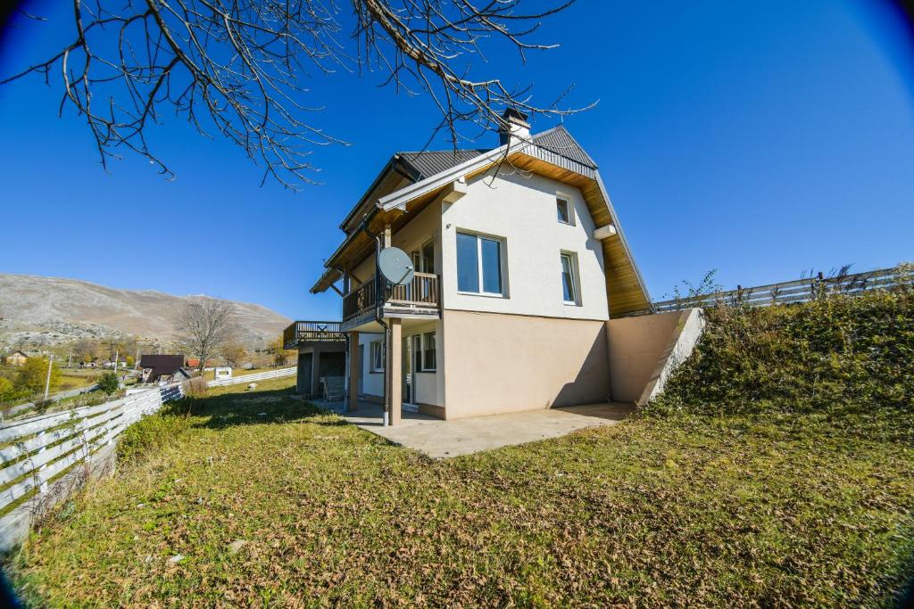 une maison blanche avec un toit en gambrel dans l'établissement Utopia Mountain resort Bjelasnica, à Bjelašnica