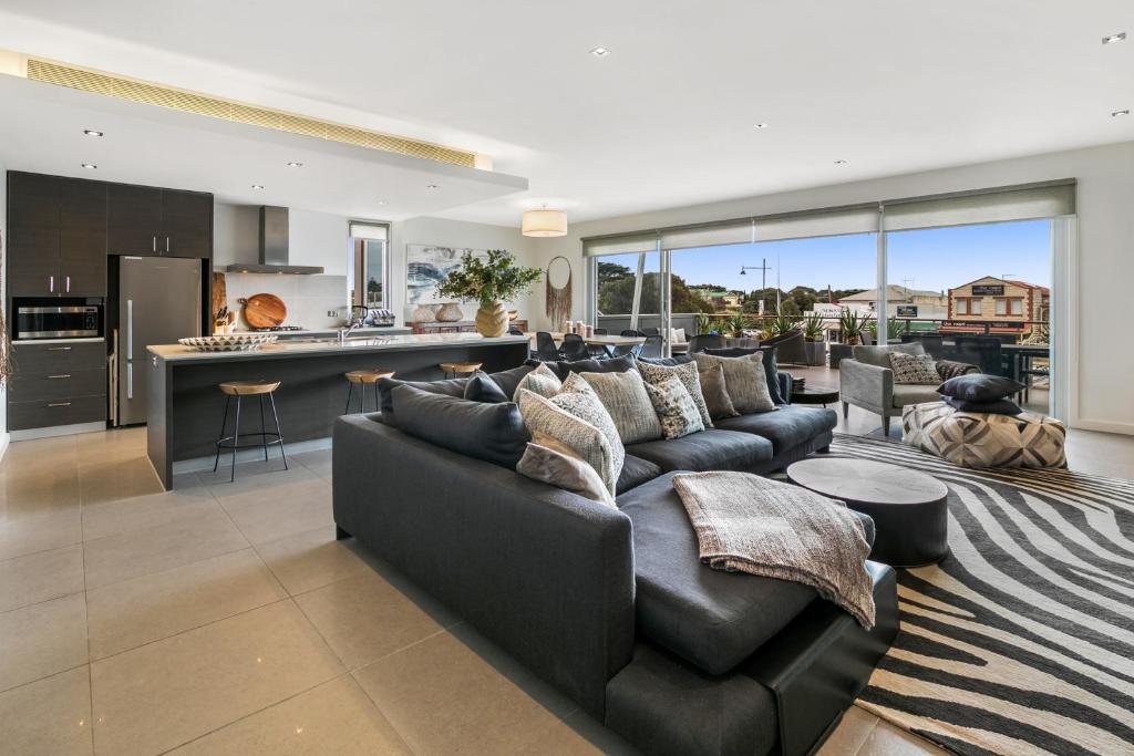 a living room with a black couch and a kitchen at Saltwater Apartment Sorrento in Sorrento