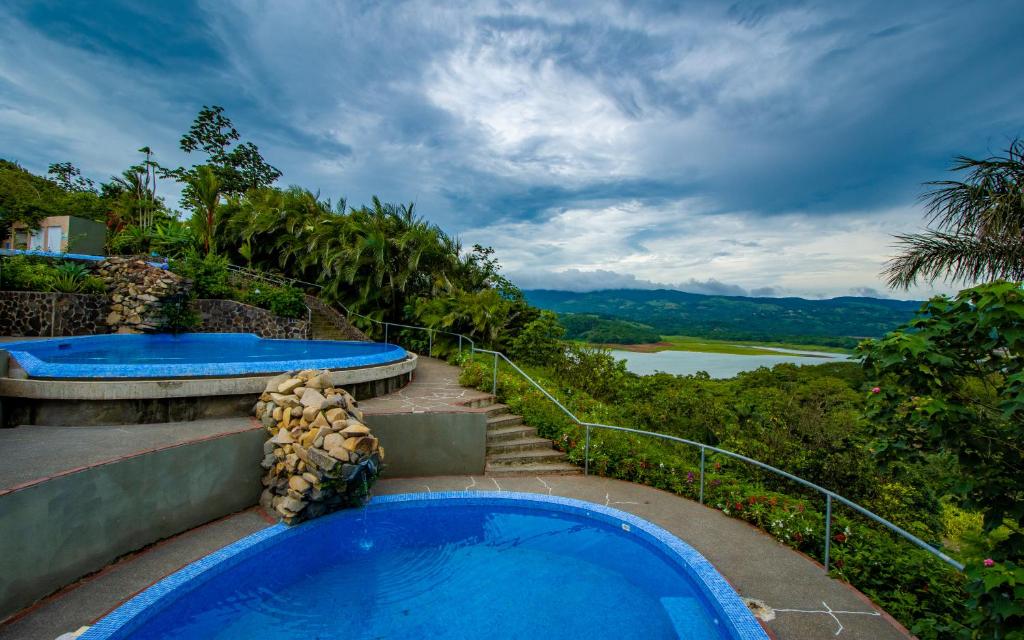 a blue swimming pool with a view of a river at Lake Arenal Condos in Naranjos Agrios