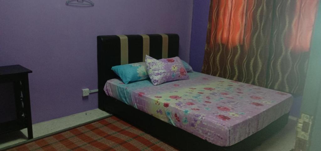 Cama pequeña en habitación con paredes moradas en Baiti Homestay, en Gambang