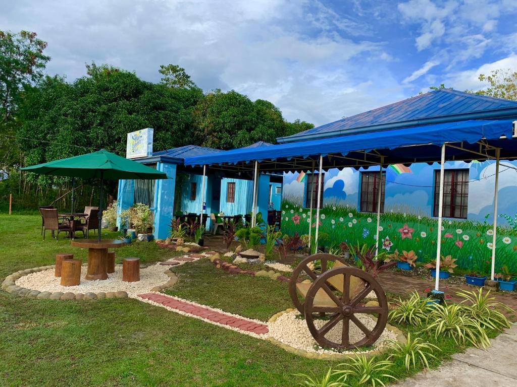 a blue building with a wheel in the grass at Blue Summer Suites in Bingag