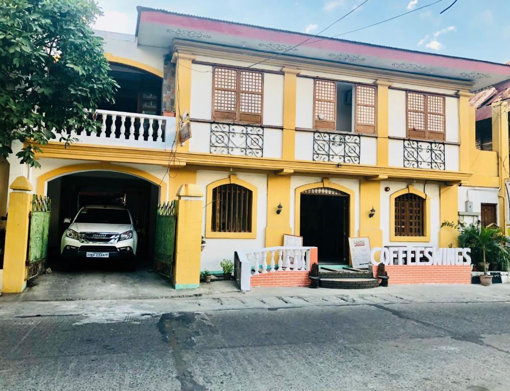 a yellow house with a car parked in the garage at COFFEESWINGS LODGING HOUSE in Vigan