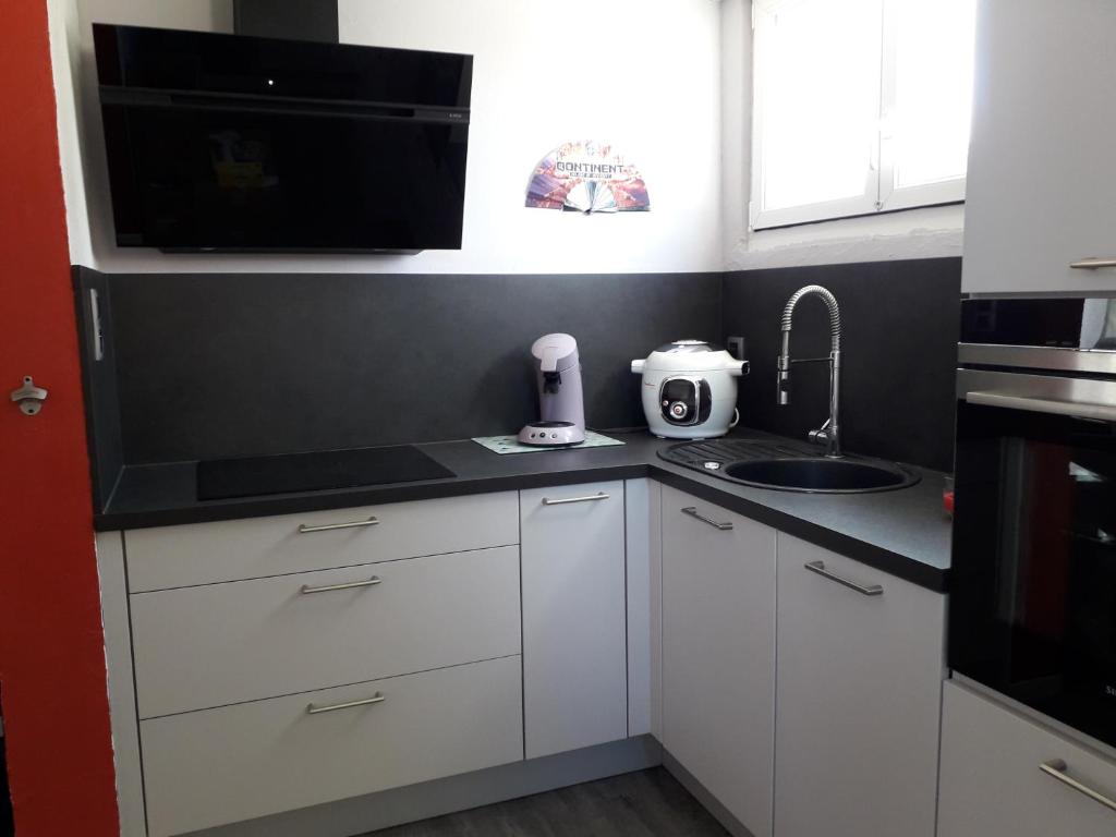 a kitchen with white cabinets and a sink and a microwave at Jolie maison de campagne in Fresnes-en-Woëvre