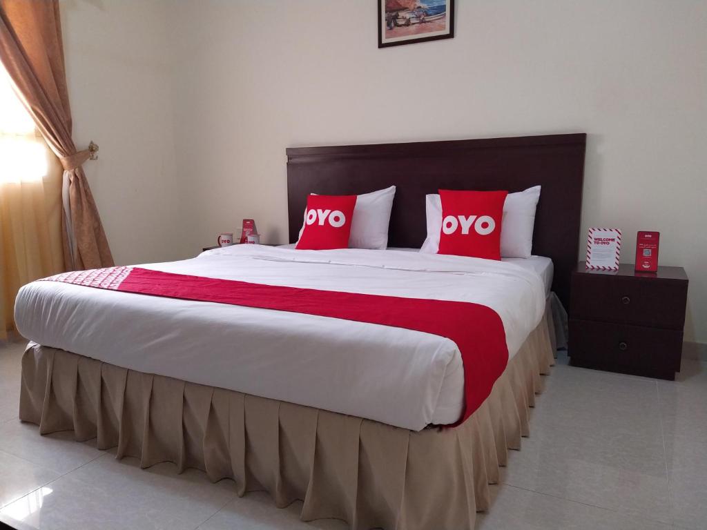 a bedroom with a large bed with red pillows at Super OYO 107 Al Areen Hotel Apartments in Shāhiq