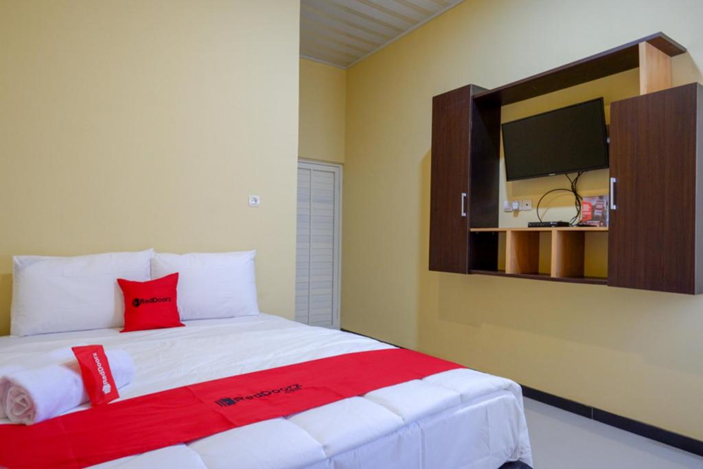 a bedroom with a large bed with a red pillow at RedDoorz Syariah near Alun Alun Pati in Pati