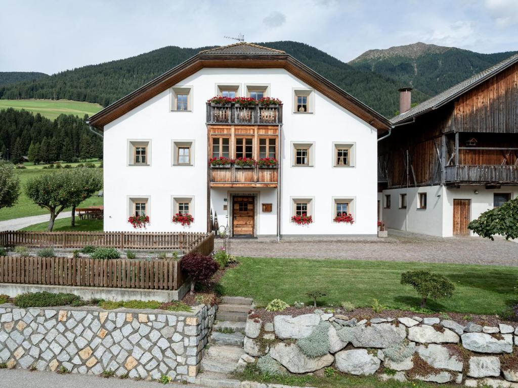 a white house with flowers on the windows at Loefflerhof in Monguelfo