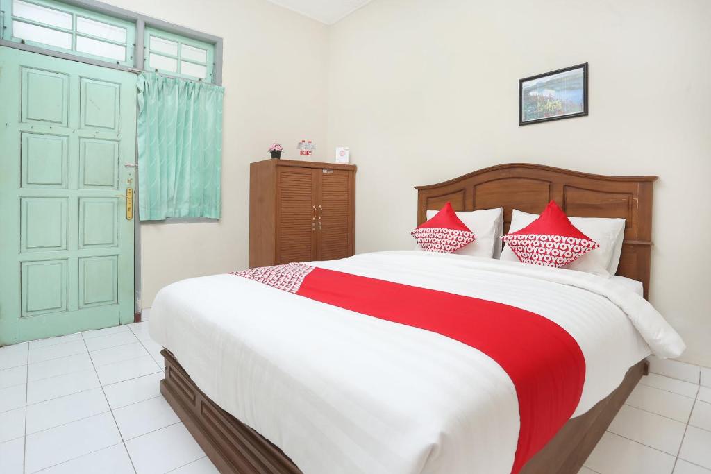 1 dormitorio con 1 cama grande con almohadas rojas y blancas en SUPER OYO 1959 Penginapan Kepurun Pawana Indonesia, en Sleman
