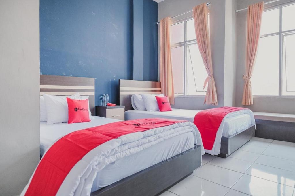 two beds in a room with blue walls and windows at RedDoorz @ Jalan Hayam Wuruk Lampung 2 in Bandar Lampung