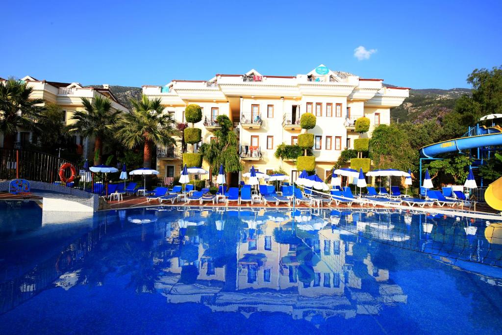 une grande piscine avec des chaises bleues et un bâtiment dans l'établissement Yel Holiday Resort, à Ölüdeniz