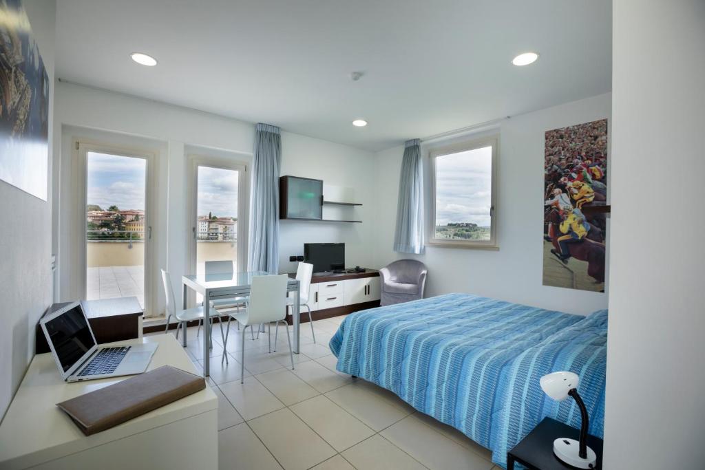 a bedroom with a bed and a desk with a laptop at Porta Pispini Residence in Siena