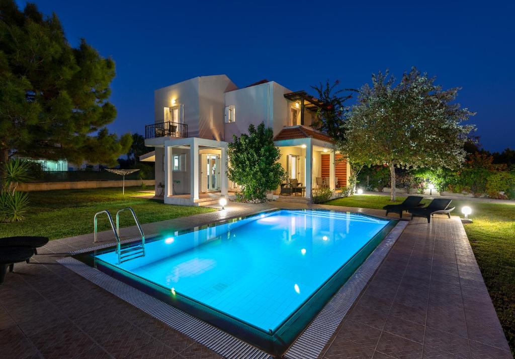 a swimming pool in front of a house at night at Afrodite Classico Villa in Kolymbia