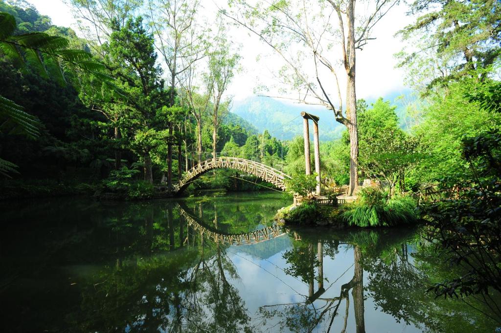 a bridge over a river with trees and water at Shante Hotel Shitou in Lugu Lake