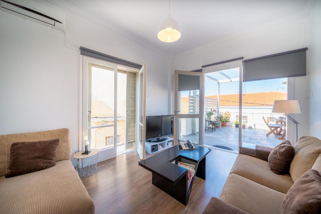 a living room with a couch and a television at The ROOF - Flat Sea View in Aegina Town in Egina