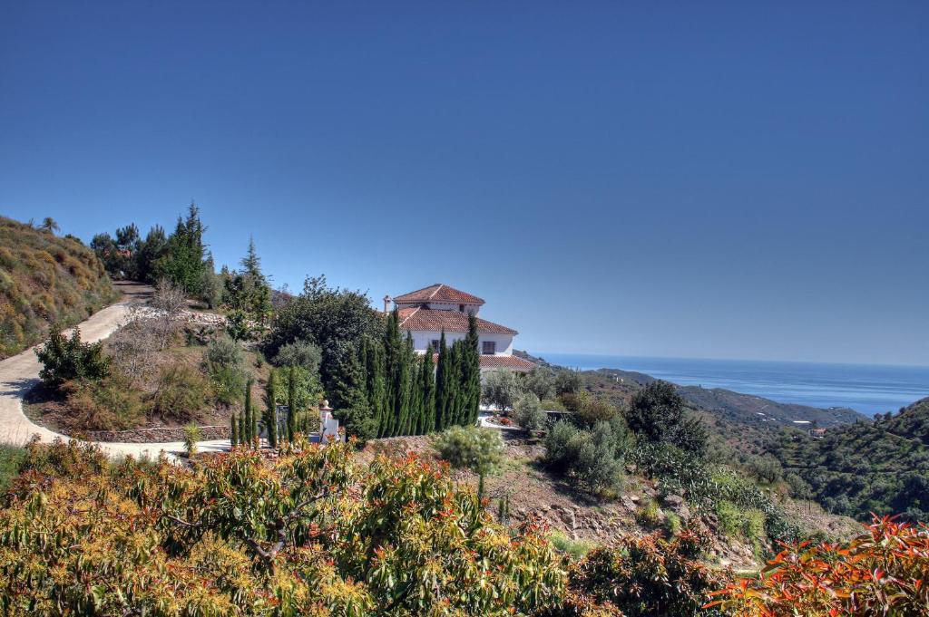 a house on a hill with the ocean in the background at Finca el Regalo in Cómpeta