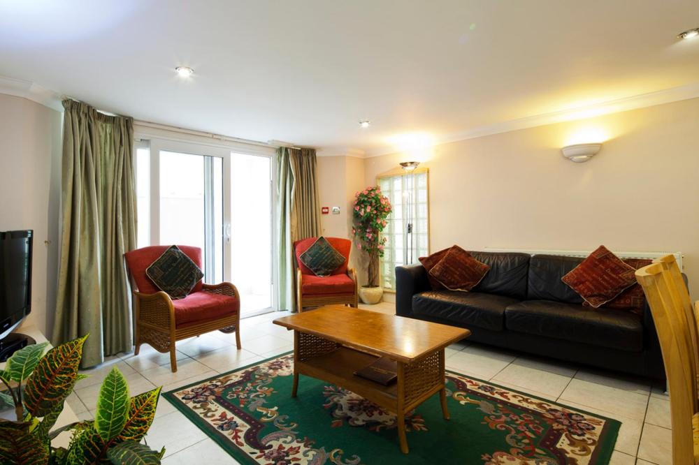 a living room with a black couch and two chairs at Burbage Holiday Lodge Apartment 1 in Blackpool