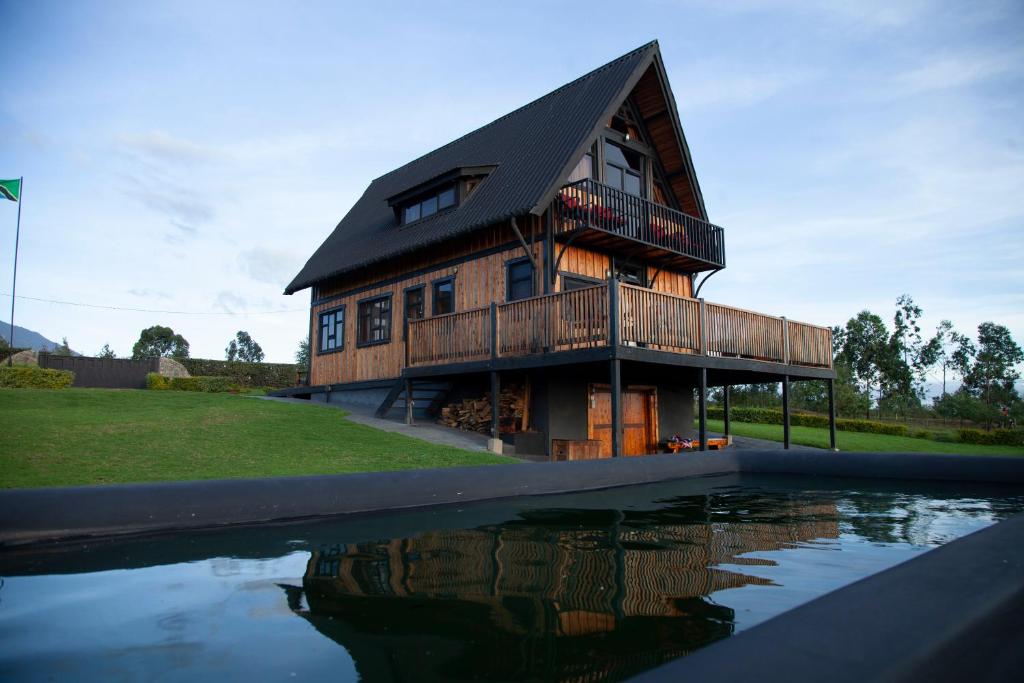 une grande maison en bois avec une réflexion dans l'eau dans l'établissement Shamba lodge, à Arusha