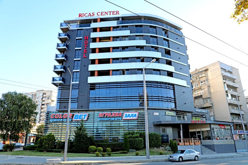 un grand bâtiment avec une voiture garée devant lui dans l'établissement Hotel Ricas, à Sliven