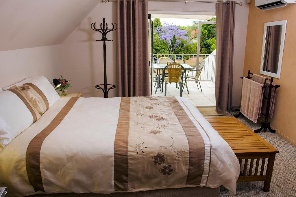 a bedroom with a bed and a balcony with a table at Yungaburra Heart B & B in Yungaburra