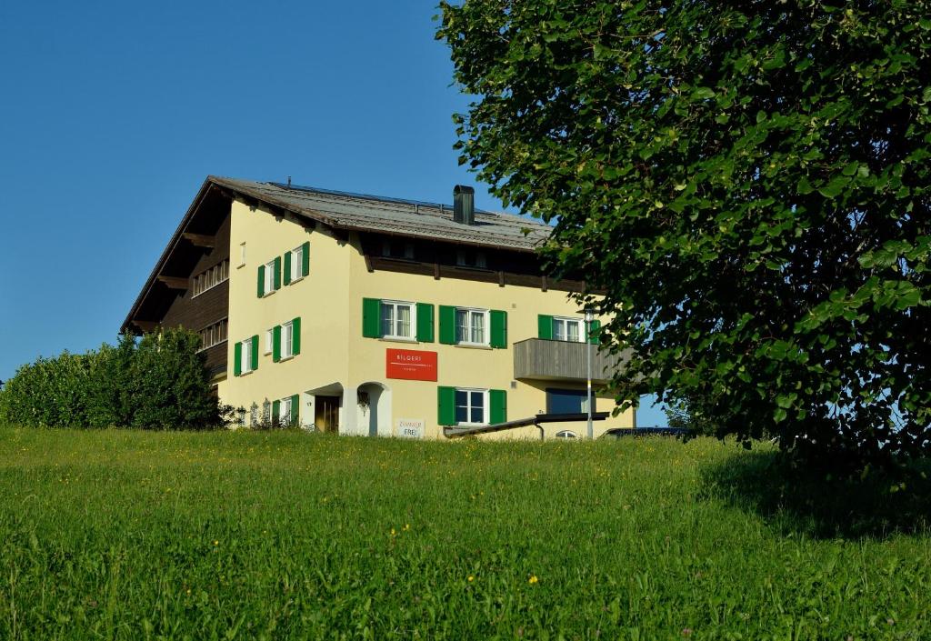 un bâtiment sur une colline avec une pelouse dans l'établissement Frühstückspension Bilgeri, à Sulzberg