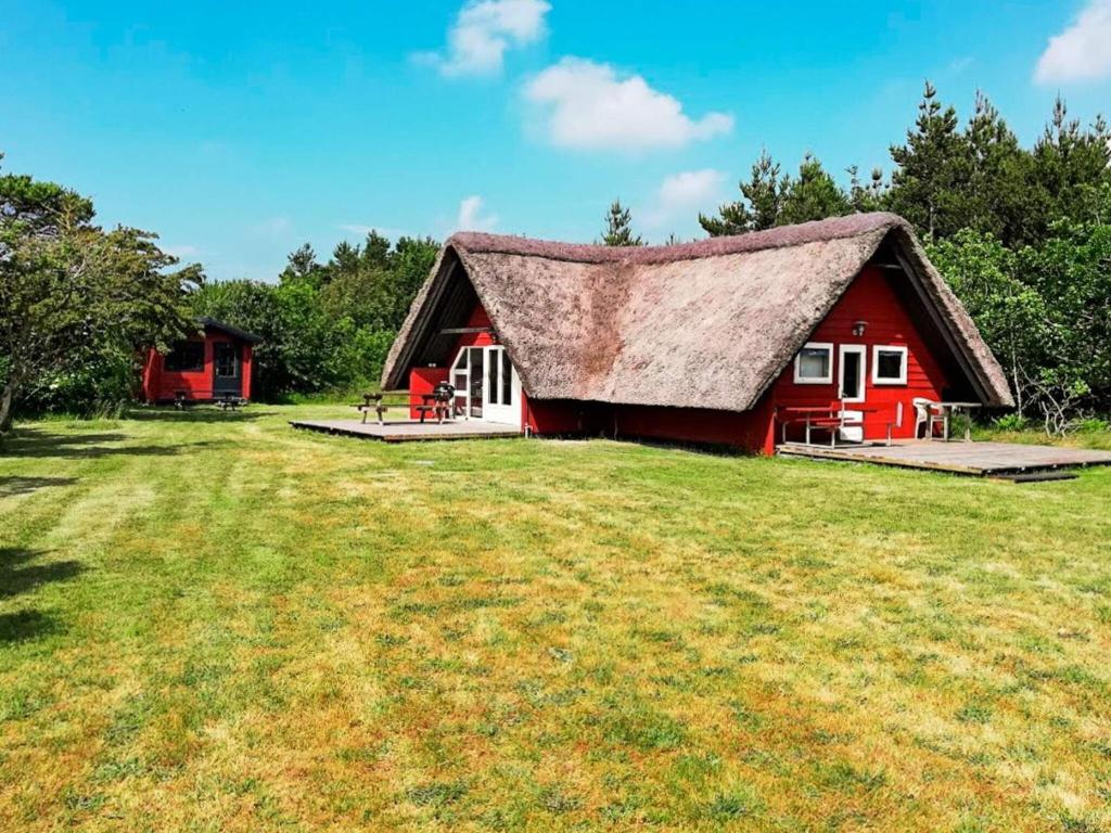 a red barn with a roof on a grass field at 6 person holiday home in R m in Toftum