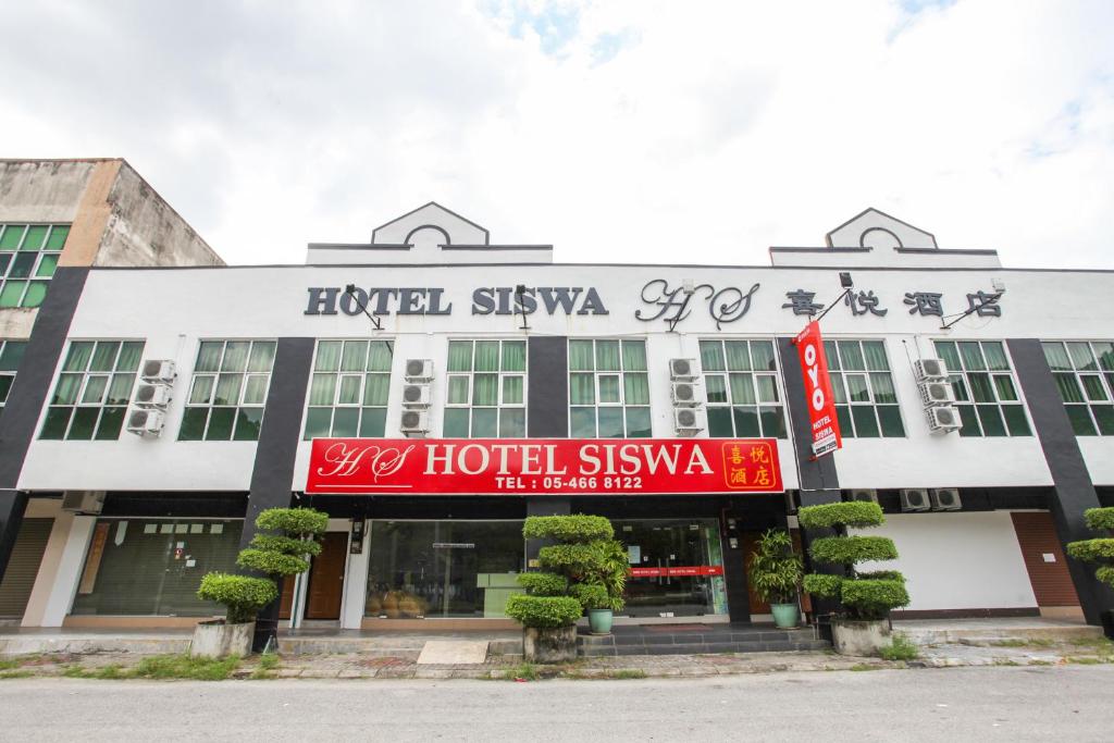 um hotel com um sinal vermelho em frente a um edifício em OYO 89539 Hotel Siswa em Kampar