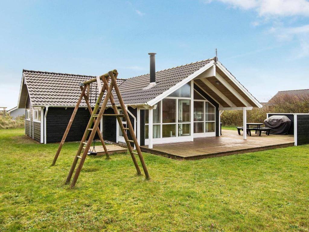 a playground in front of a small house at 8 person holiday home in Harbo re in Harboør