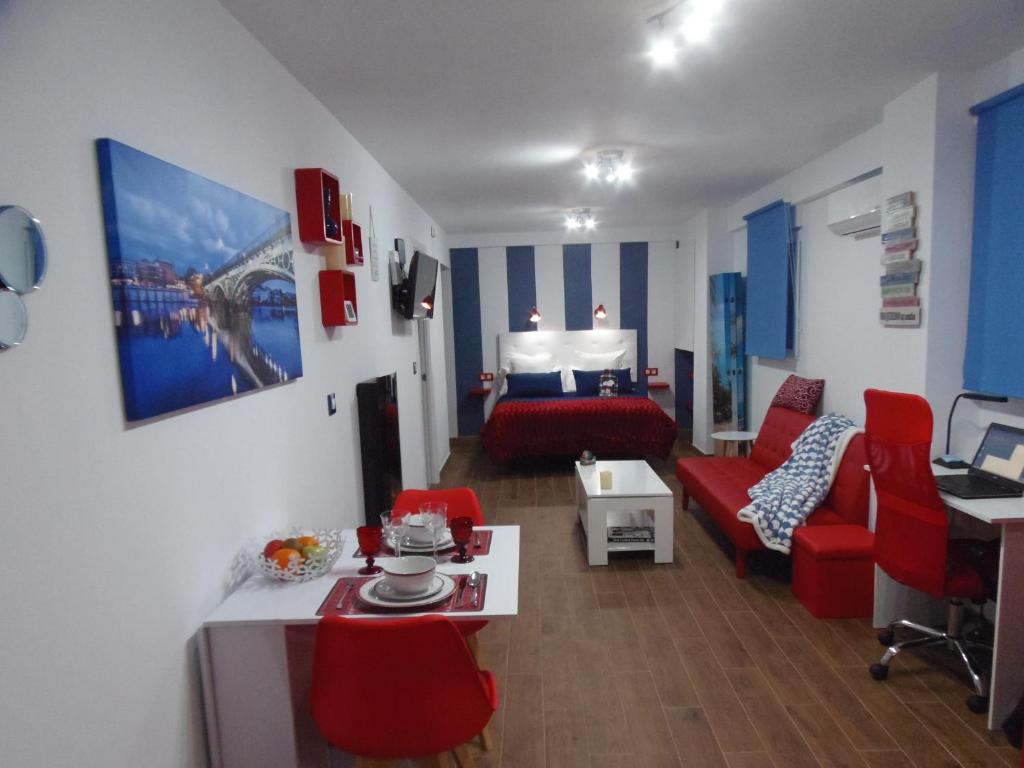 salon z czerwoną kanapą i łóżkiem w obiekcie Apartamento en Triana w Sewilli