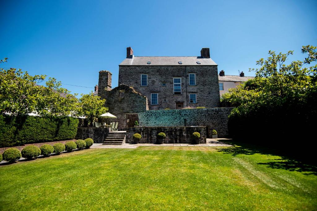 uma antiga casa de pedra com um jardim de relva em Great House - Grand Georgian House With Outdoor Heated Pool em Laugharne