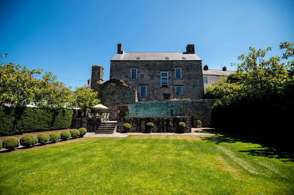 an old stone house with a grass yard at Great House - Grand Georgian House With Outdoor Heated Pool in Laugharne