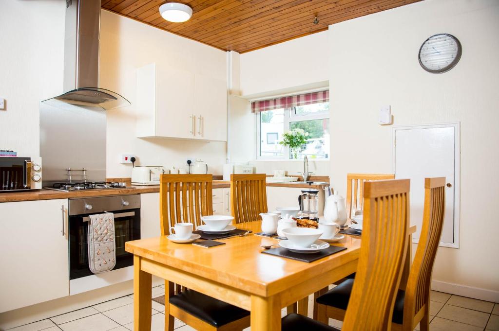 a kitchen with a wooden dining table and chairs at Awel Taf- Central cottage ideal for families, with parking in St Clears