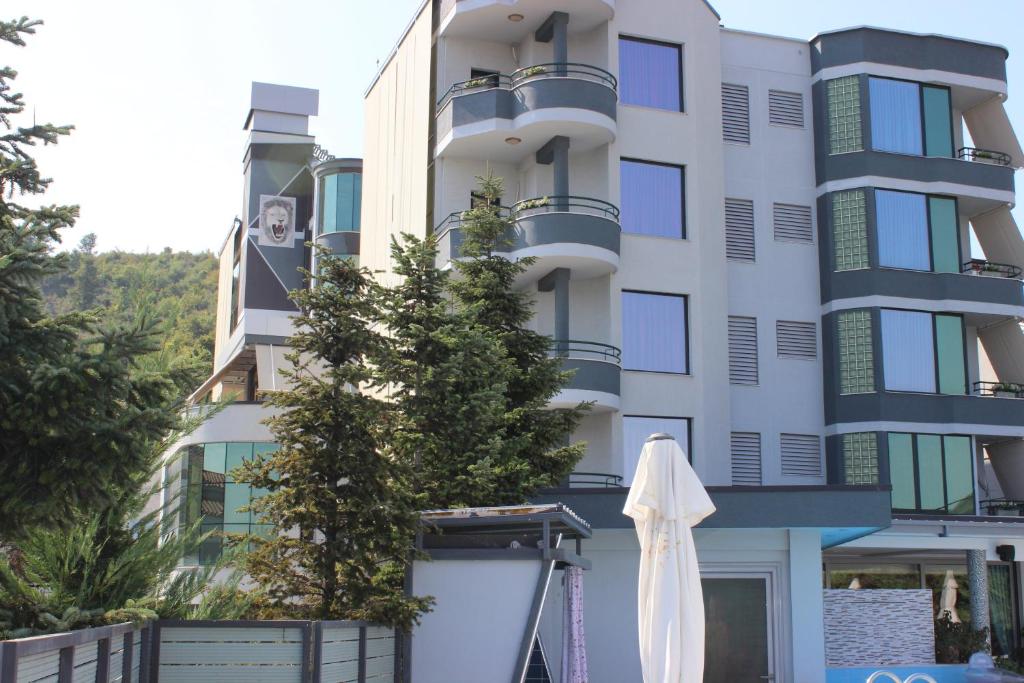 un bâtiment avec un parasol blanc devant lui dans l'établissement Luander Hotel, à Tirana
