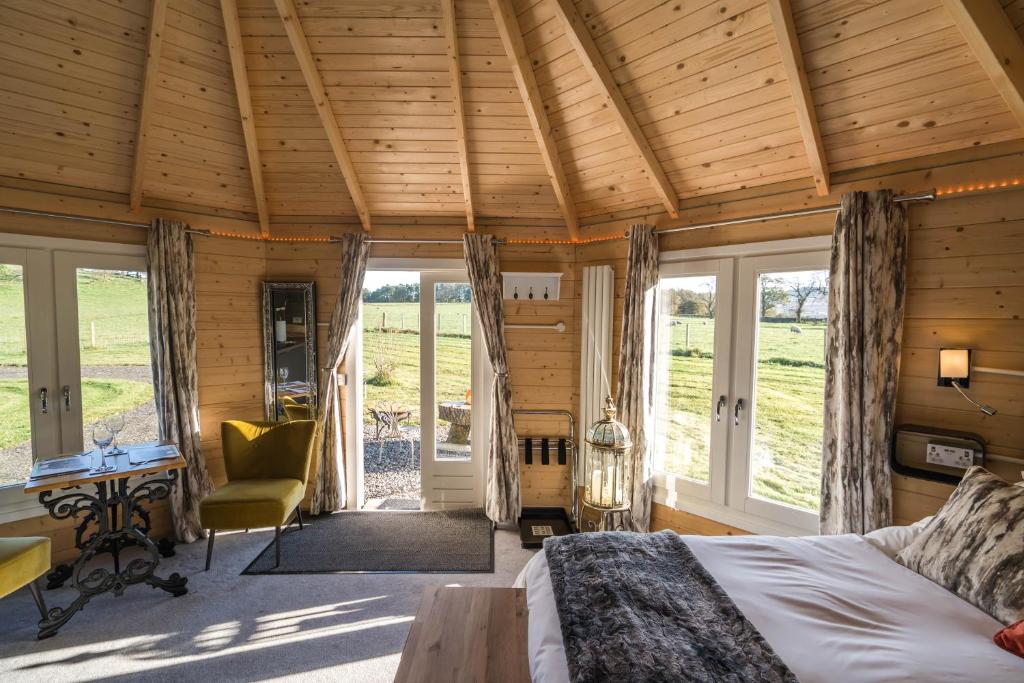 a bedroom with a bed and a desk and windows at Dunroamin Lodges in Drymen