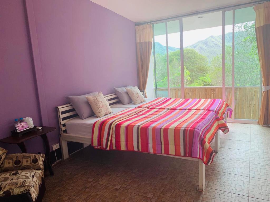 a bedroom with a bed with a striped blanket and a window at Pai Yard Guest House in Pai