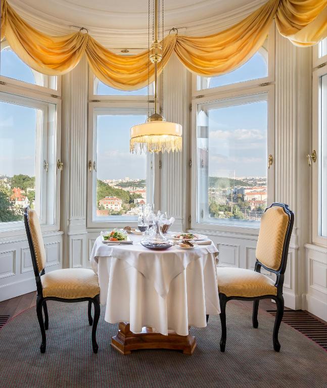 a dining room with a table and two chairs and windows at Le Palais Art Hotel Prague in Prague