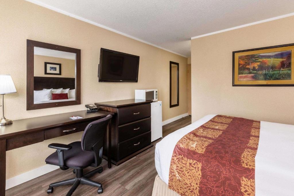 a hotel room with a bed and a desk and a computer at Ramada by Wyndham Coquitlam in Coquitlam