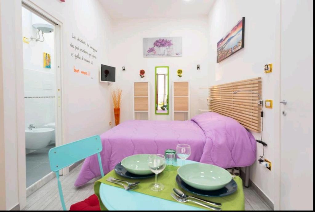 um pequeno quarto com uma cama roxa e uma mesa em Flower Power em Nápoles