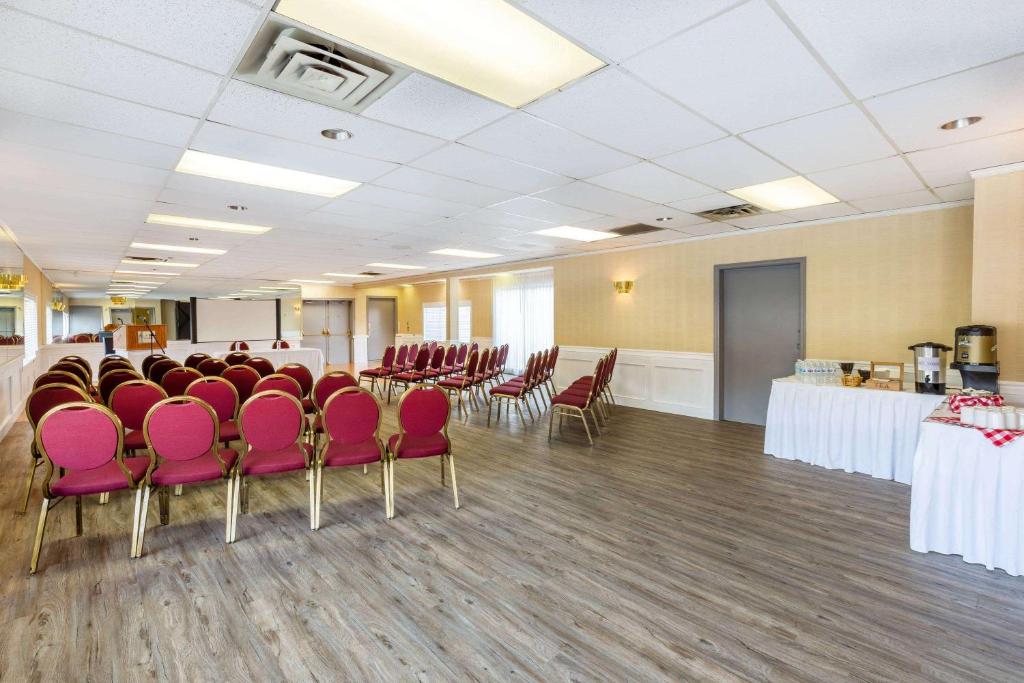 a conference room with red chairs and tables in a room at Ramada by Wyndham Coquitlam in Coquitlam
