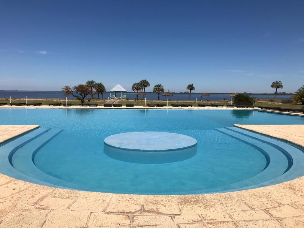 a large swimming pool with blue water at Club del Campo El Faro Studio 15 in Carmelo