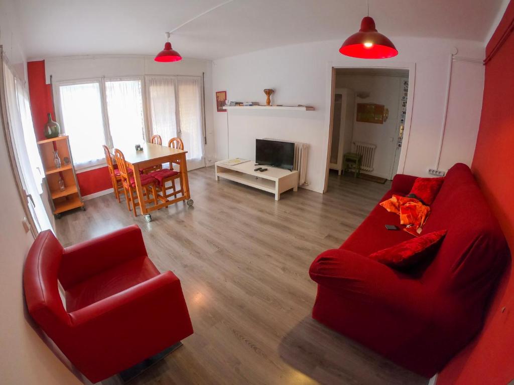 ein Wohnzimmer mit einem roten Sofa und einem Tisch in der Unterkunft Piso luminoso y moderno a un minuto del río (Sort) in Sort